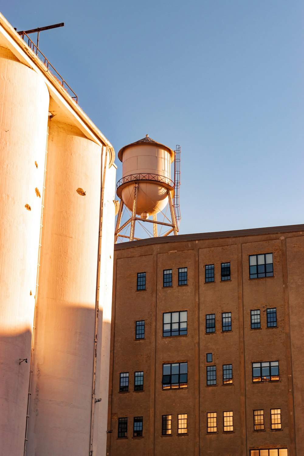 white water tank beside brown concrete building during daytime
