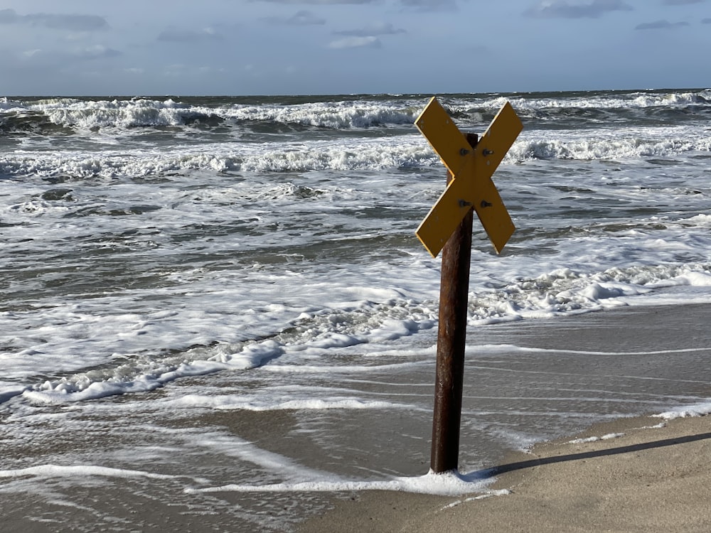 brown wooden cross on white snow covered ground near sea during daytime