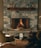 A cozy stone fireplace with a warm fire burning, surrounded by elegant decor. The mantel features decorative bird sculptures, and two plush chairs face a small round table with a framed picture or menu. The ambiance is inviting and luxurious, with soft lighting enhancing the stone textures.