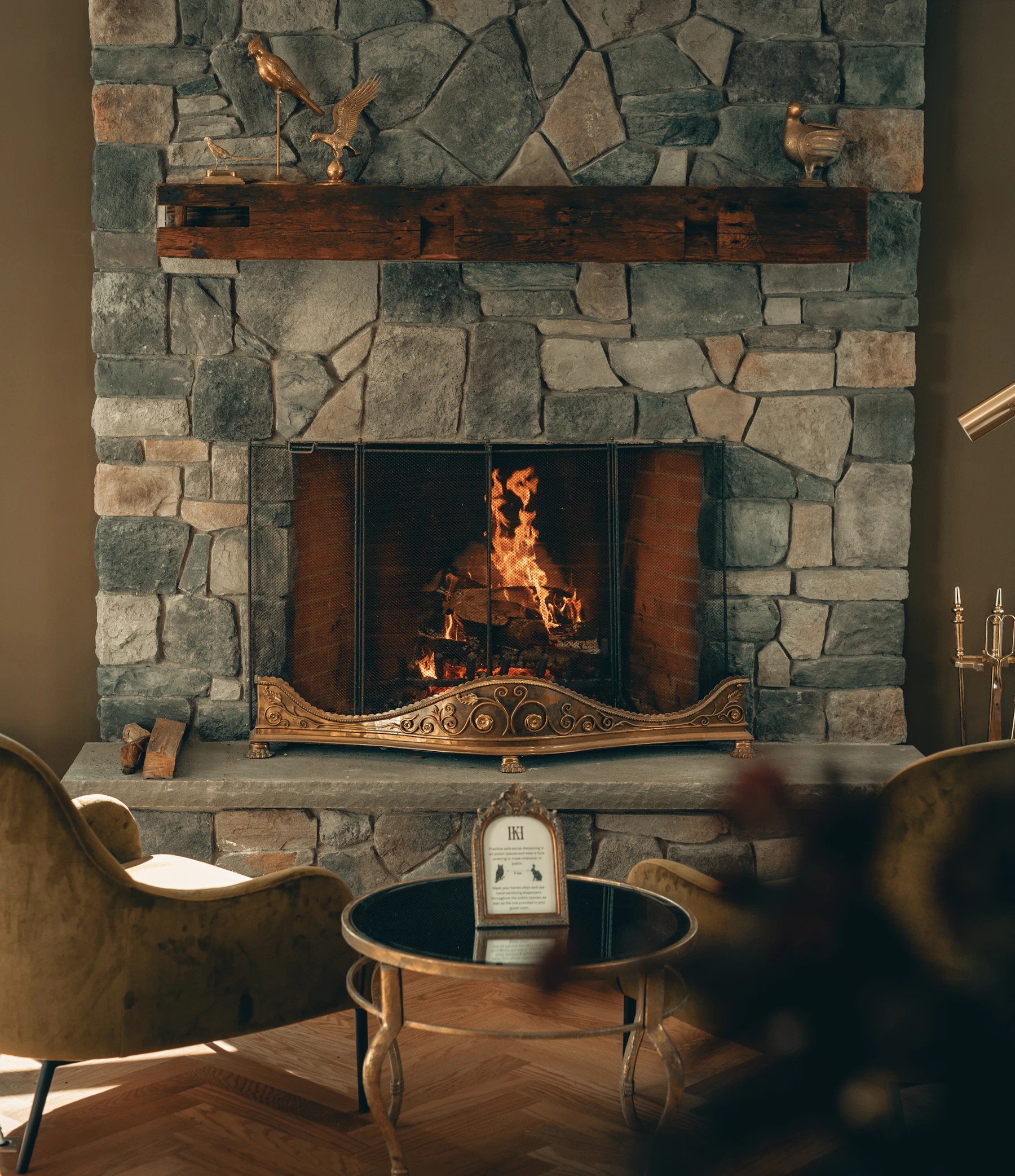 Stone fireplace with screen and warm flame in an interior room