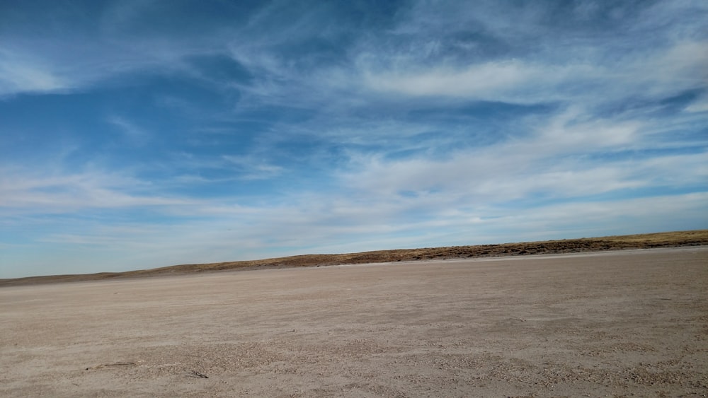 brown field under blue sky and white clouds during daytime