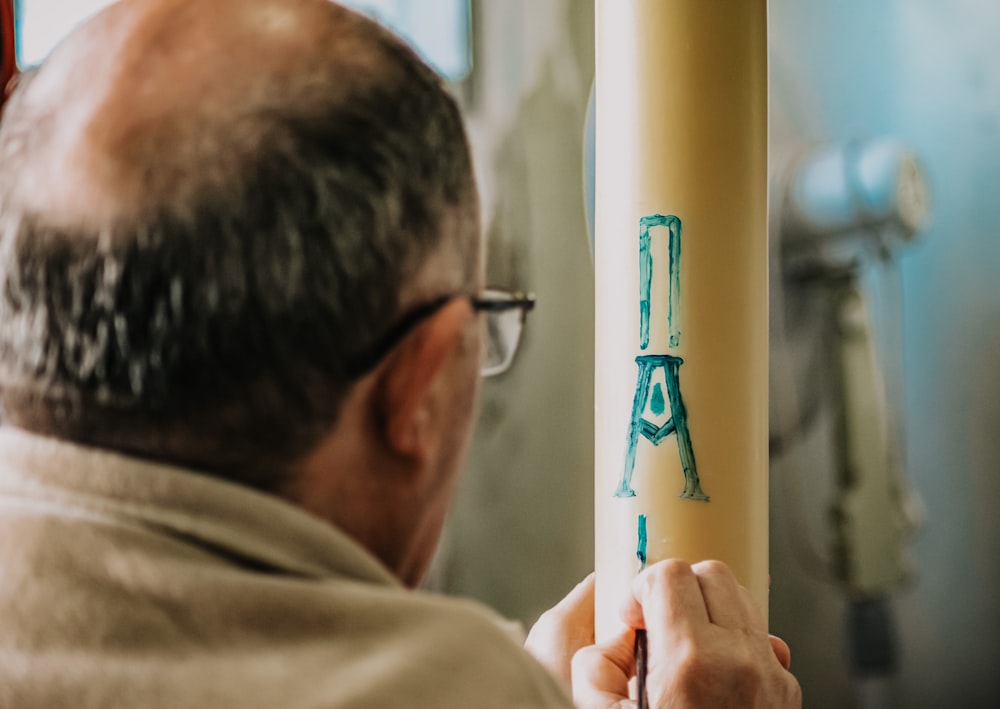 man in brown shirt holding blue and white stick