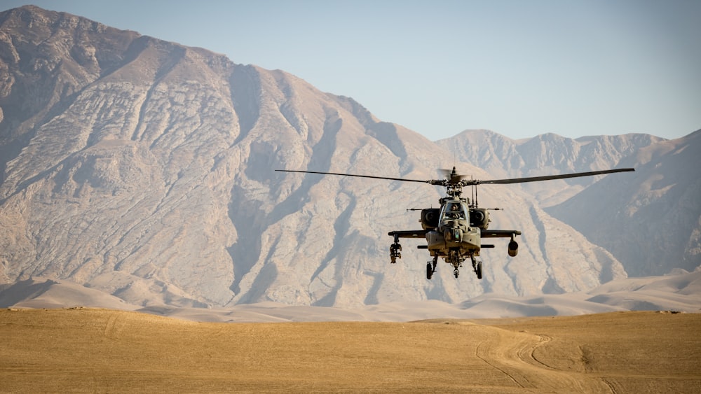 昼間に茶色の野原の上を飛ぶ黒いヘリコプター