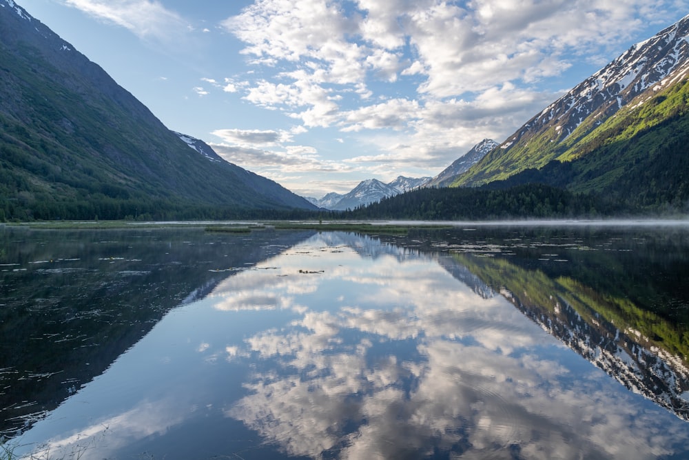 green mountains beside body of water under blue sky during daytime