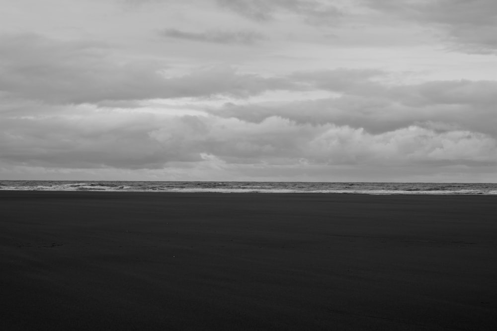 grayscale photo of sea under cloudy sky