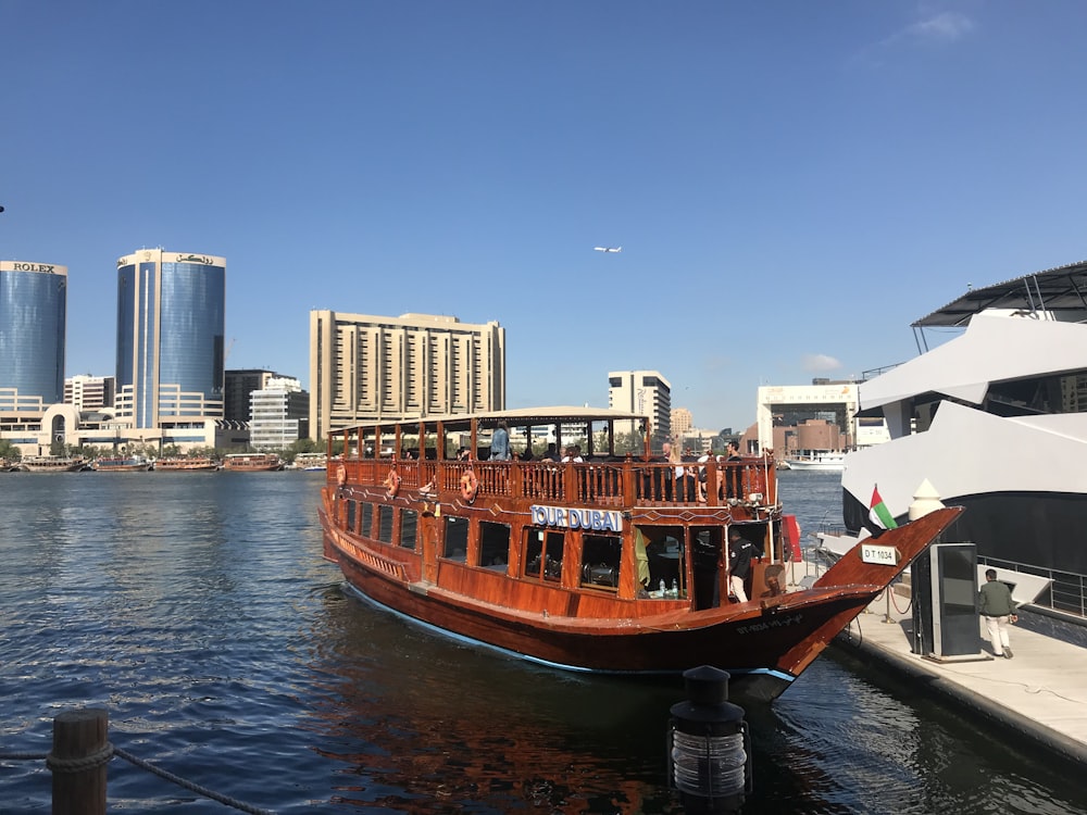 brown boat on body of water near city buildings during daytime