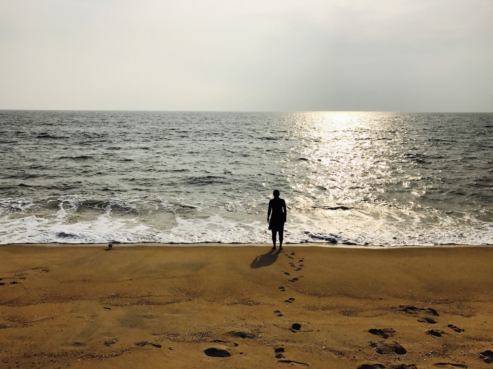 person in black jacket walking on beach during daytime