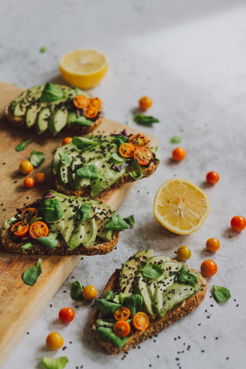 sliced pizza with green vegetable and lemon on brown wooden chopping board