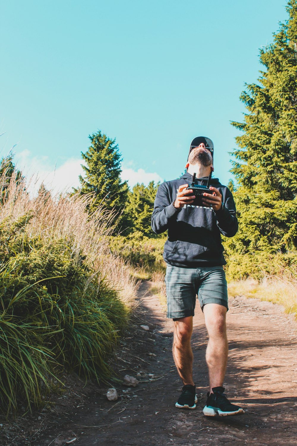 man in black t-shirt and blue denim shorts holding black dslr camera