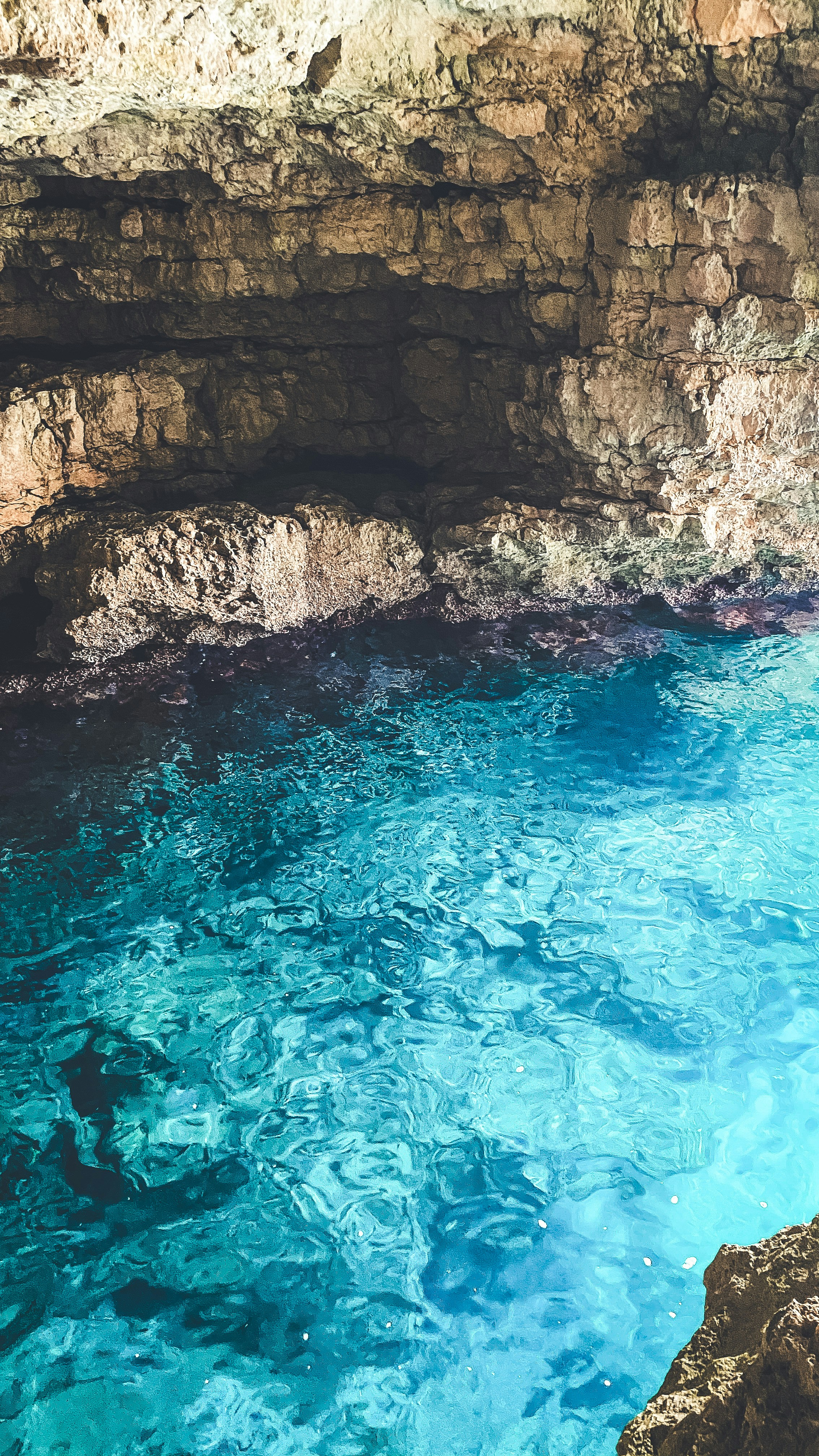 brown rock formation beside blue water