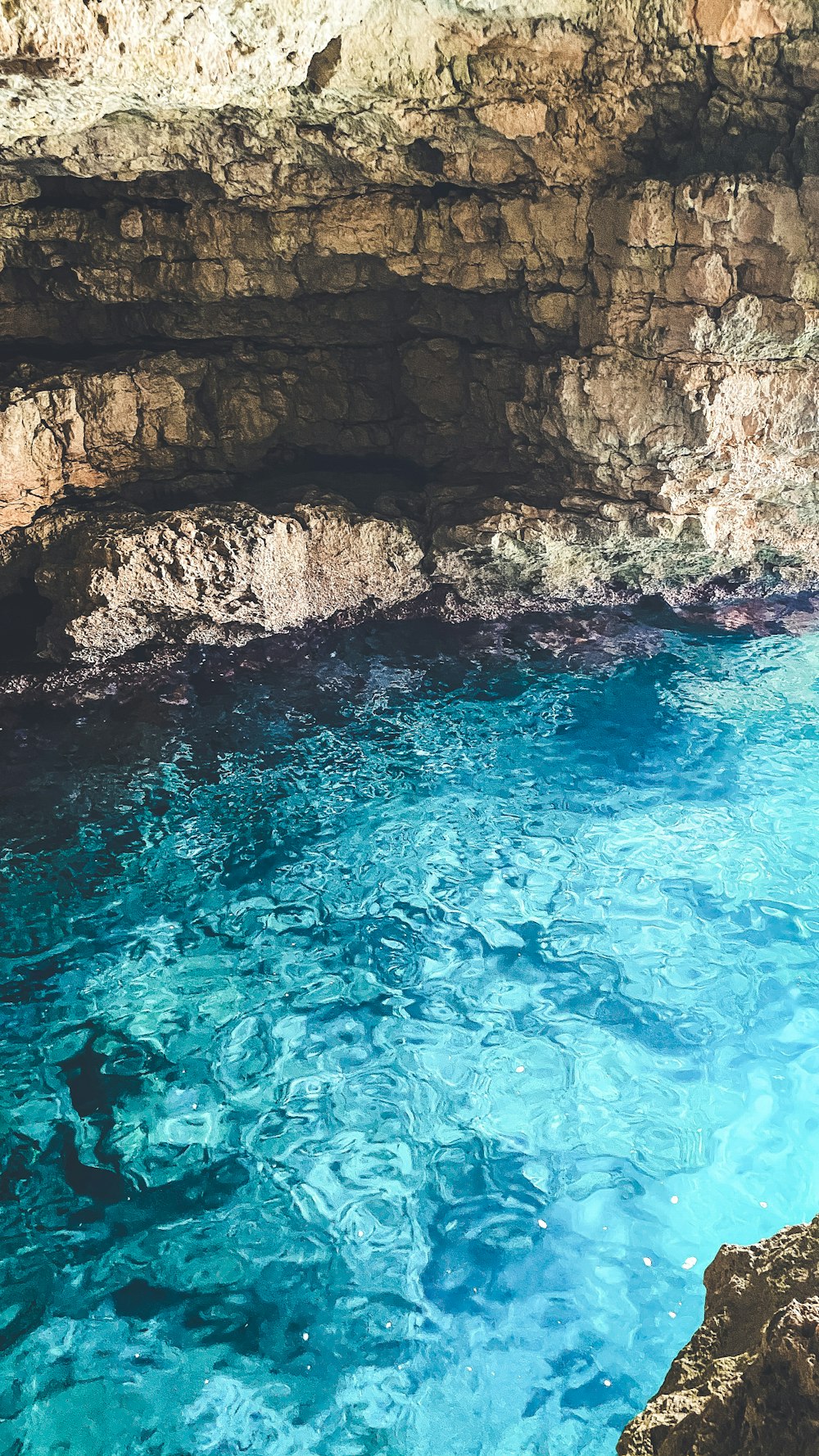 brown rock formation beside blue water