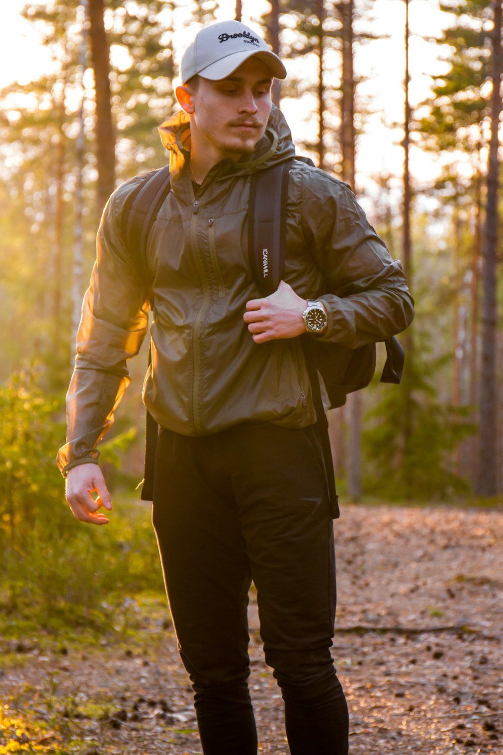 Mann in grüner Jacke und schwarzer Hose steht tagsüber im Wald