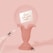 A decorative pedestal with an ornate design holds a transparent sphere featuring a message that reads 'Don't hide your magic.' Two black spiders and cobwebs add an eerie touch to the pastel pink setup.