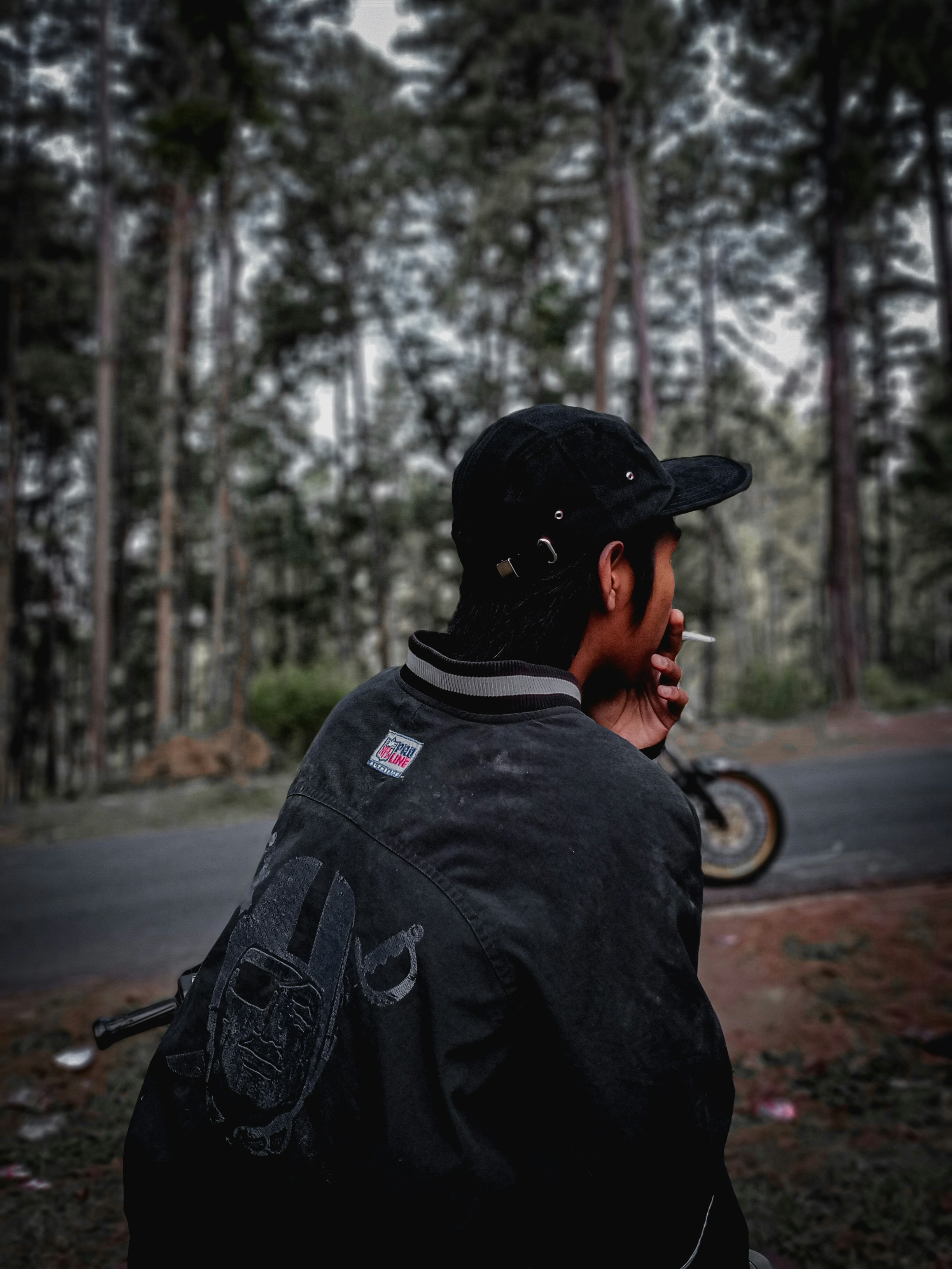 man in black jacket wearing black cap standing on road during daytime