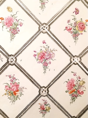 The image features a pattern with floral bouquets inside diamond-shaped frames. Each bouquet contains a variety of flowers, including roses and other delicate blooms, arranged in a visually appealing manner. The flowers are in shades of pink, red, yellow, and green, and are set against a cream or light-colored background, giving it a classic and elegant look.