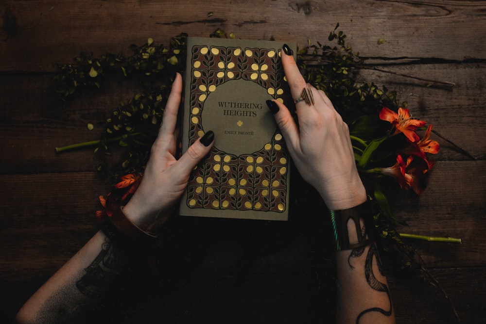 person holding black and gold book