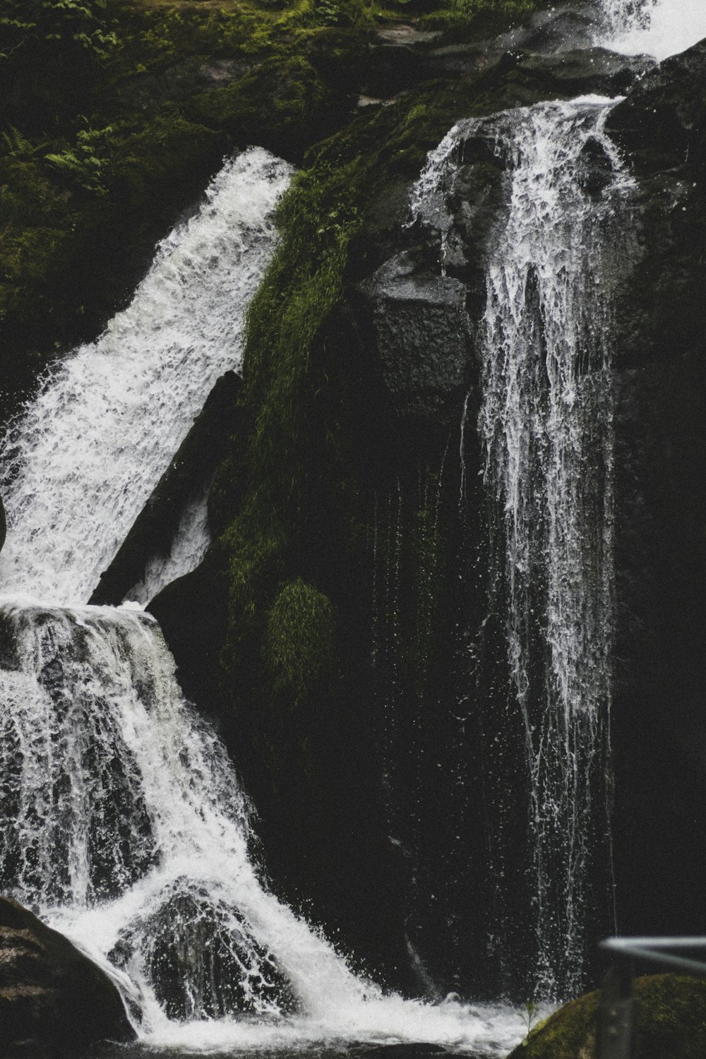 waterfalls in the middle of green moss covered rocks