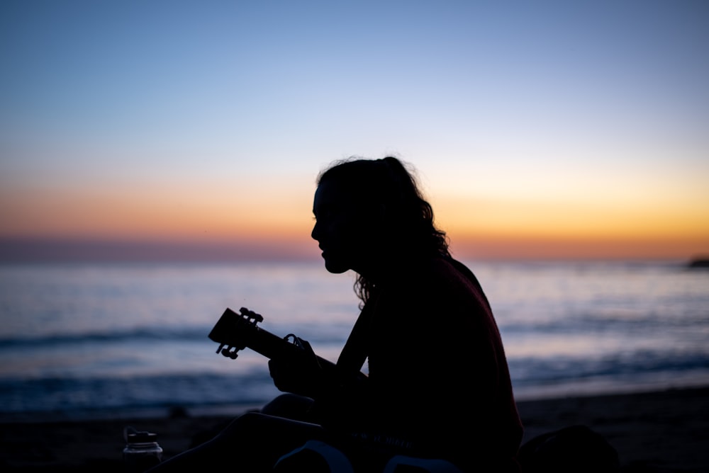 silhouette of woman holding camera during sunset