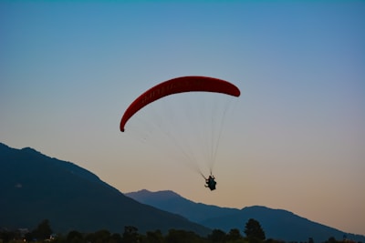 person in red parachute over mountains during daytime