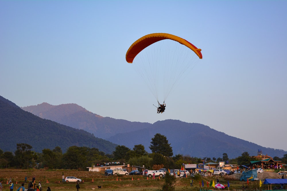 people on yellow parachute over green mountains during daytime