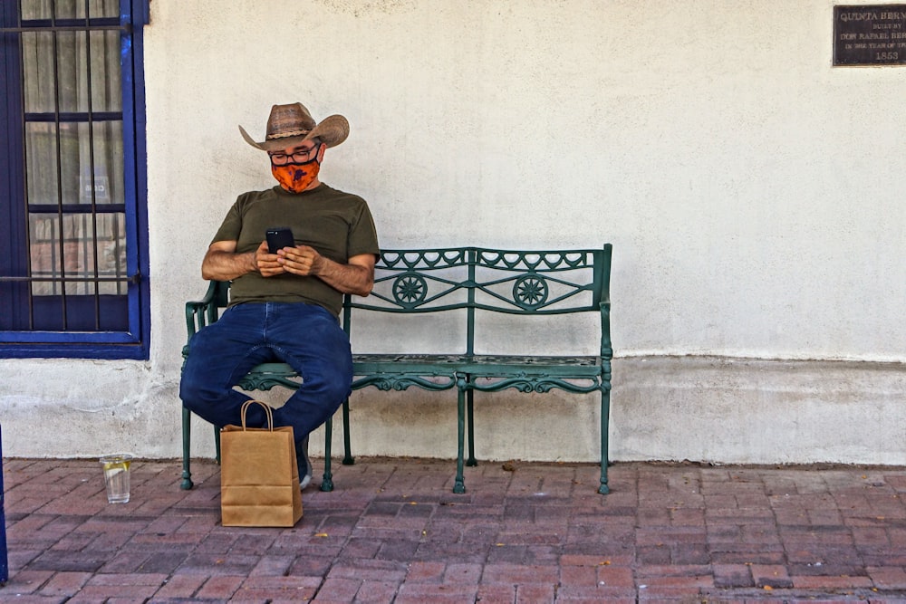 man in blue t-shirt and blue denim jeans sitting on black metal bench