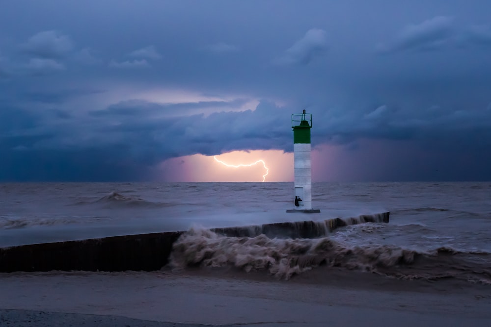 farol branco e vermelho no chão coberto de neve branca durante o dia