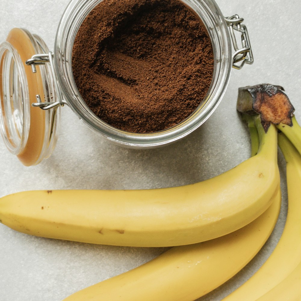 fruta de banana amarela ao lado de caneca de vidro transparente