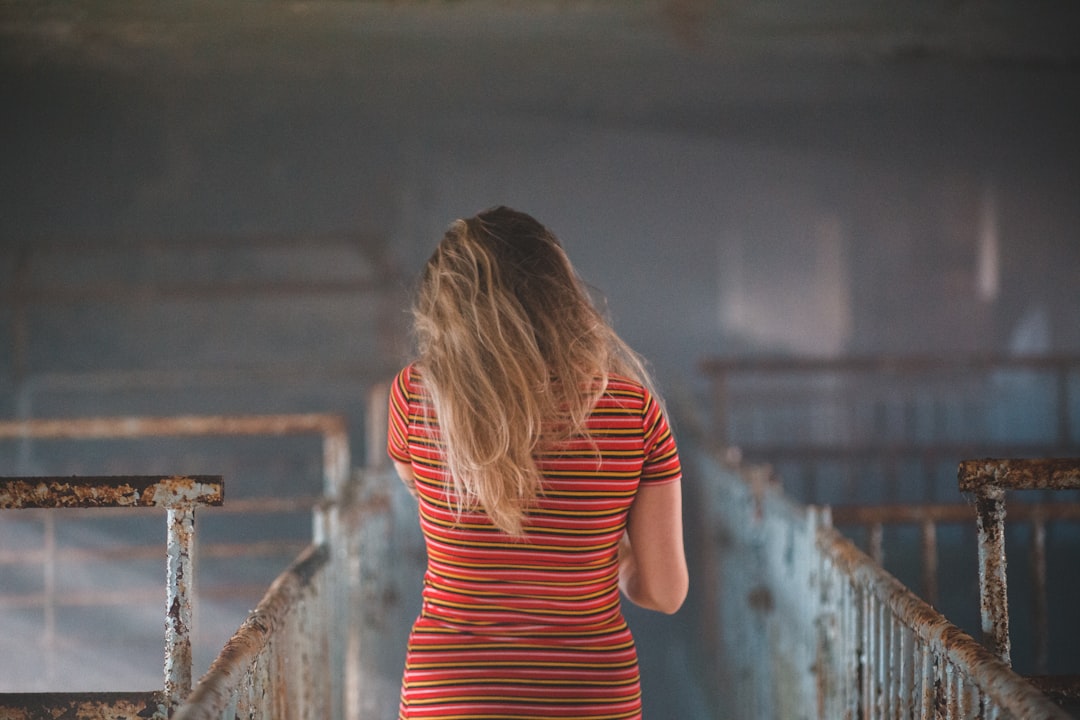 woman in red and white striped shirt standing on brown wooden bridge
