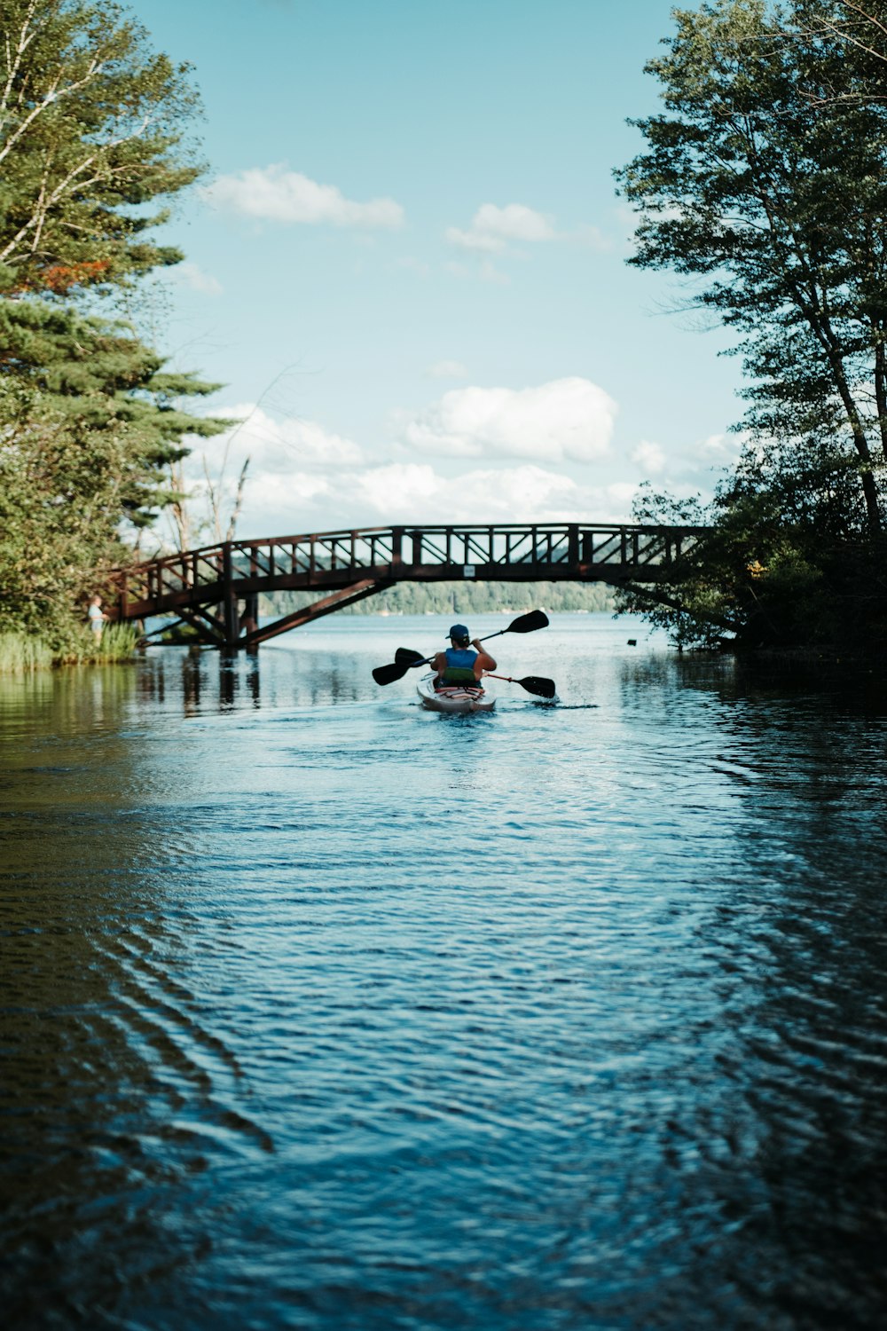 uomo che cavalca in kayak sul fiume sotto il ponte durante il giorno