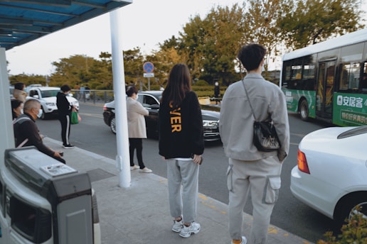 man in black crew neck t-shirt and white pants standing beside woman in white pants