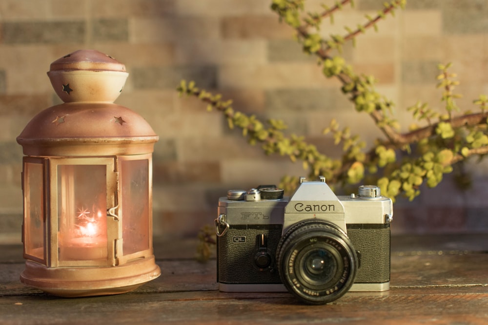 black and silver dslr camera beside brown candle holder