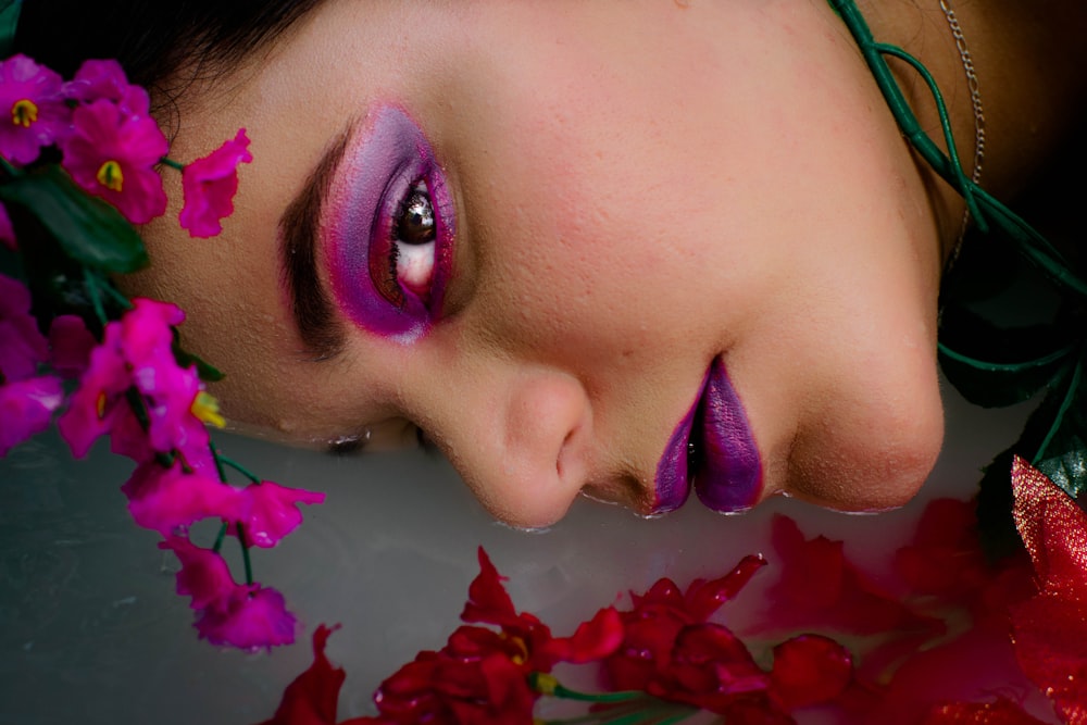 woman in green shirt lying on white ceramic bathtub with red petals