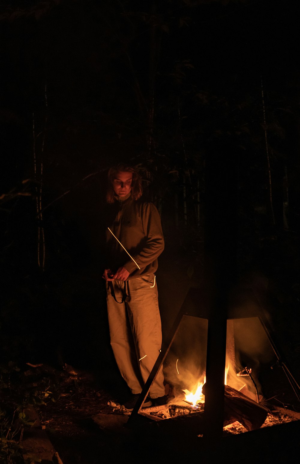 woman in brown coat standing near bonfire