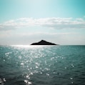 body of water near mountain under blue sky during daytime