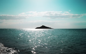 body of water near mountain under blue sky during daytime