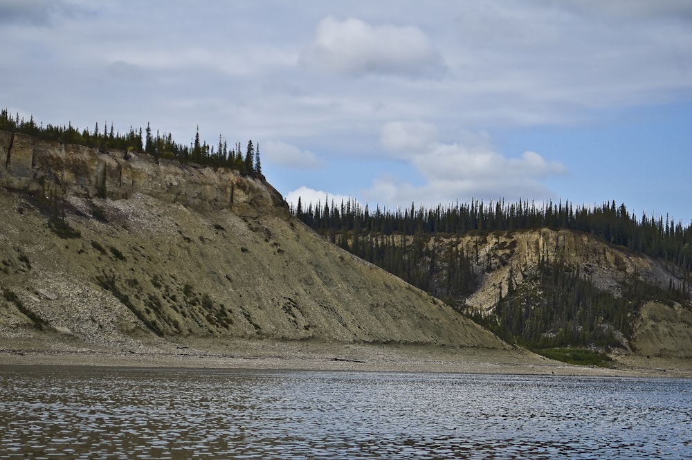 green and brown mountain beside body of water during daytime