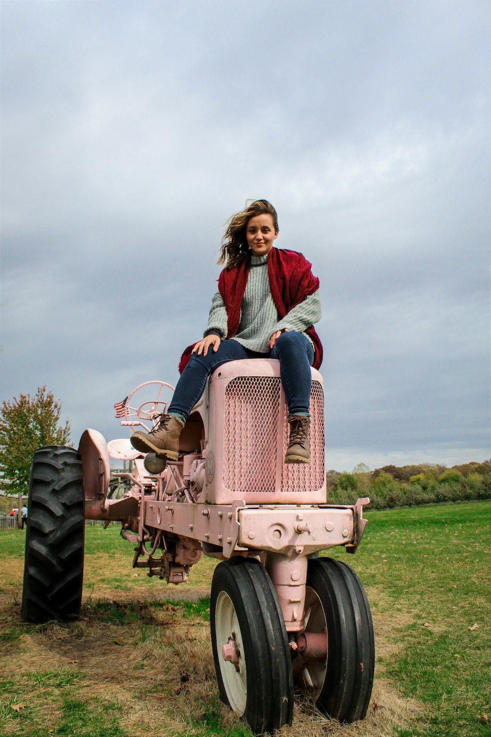 woman in red long sleeve shirt riding red tractor on green grass field during daytime