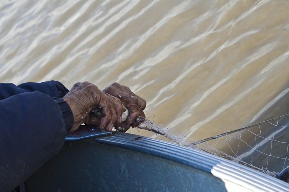 man in blue long sleeve shirt and blue denim jeans sitting on blue boat during daytime