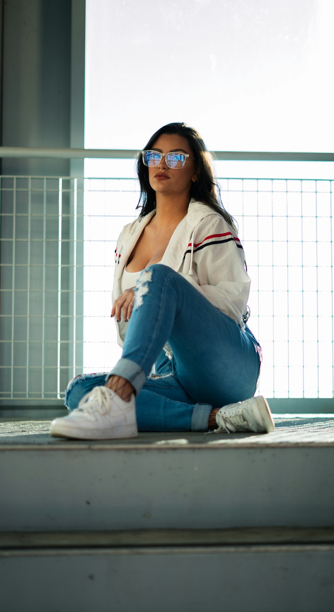 woman in blue denim jeans and white leather jacket wearing black sunglasses
