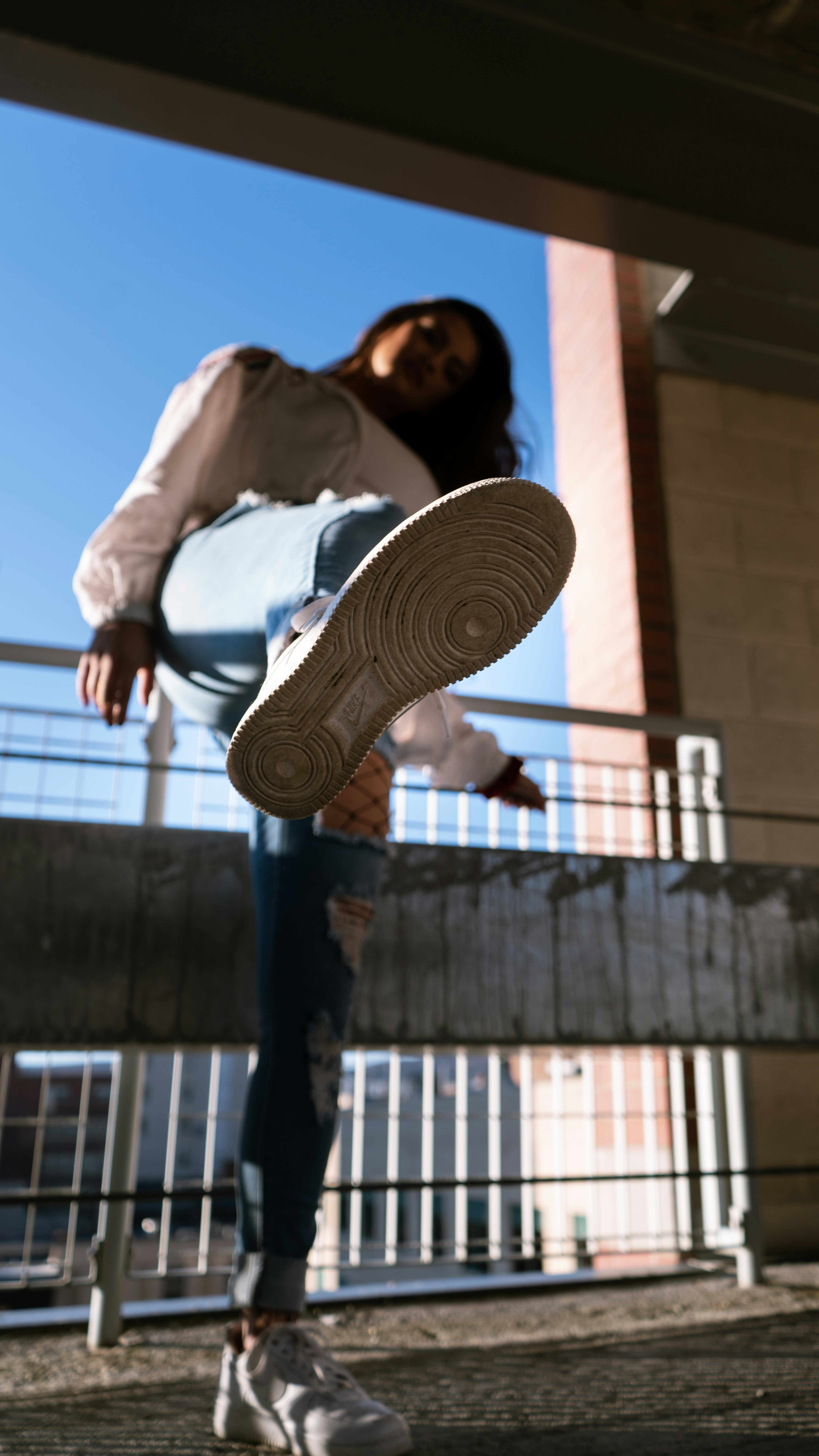 woman in white long sleeve shirt and blue denim jeans standing on brown concrete building during