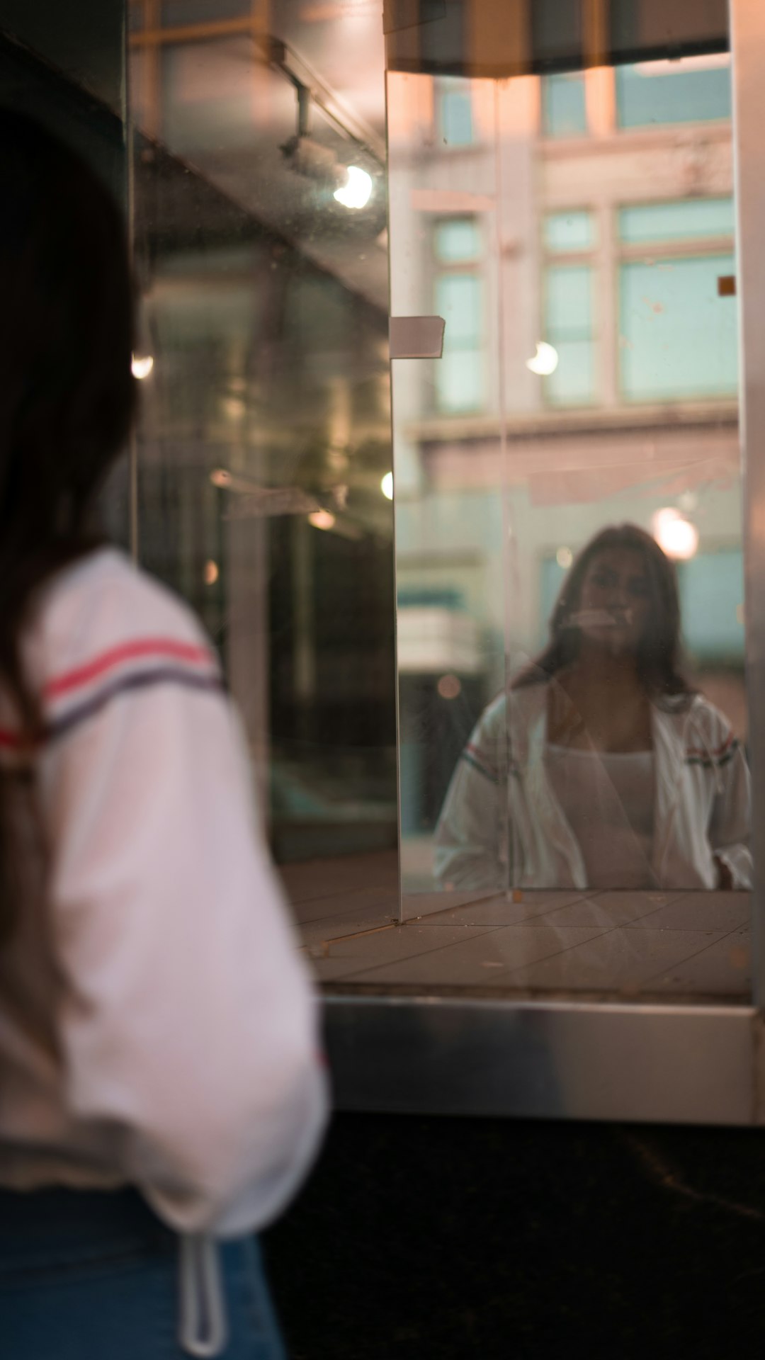 woman in white and red long sleeve shirt standing beside glass window