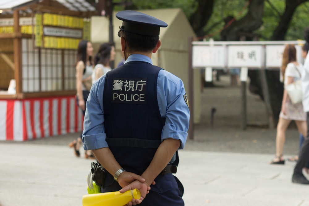 man in blue dress shirt and black pants carrying yellow plastic basin