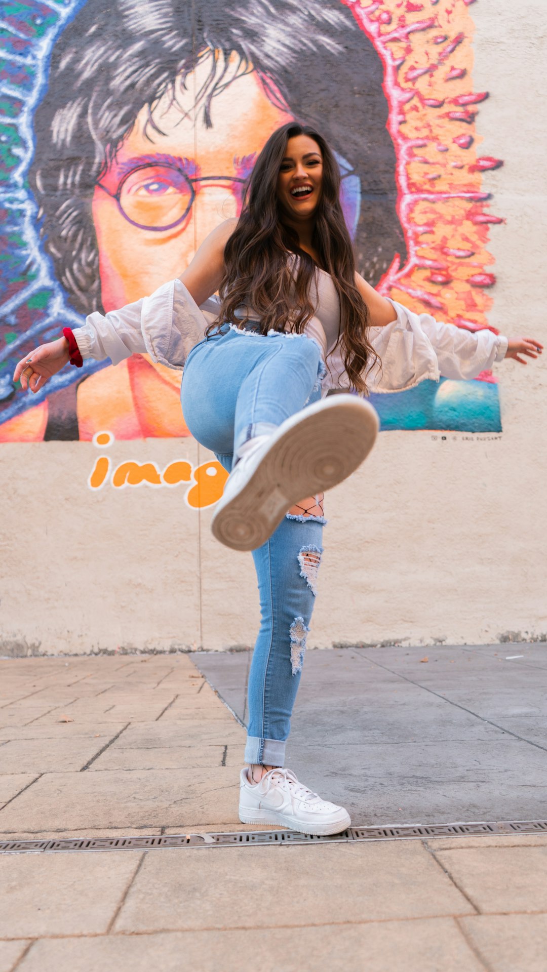 woman in blue denim jeans and gray shirt sitting on concrete wall during daytime