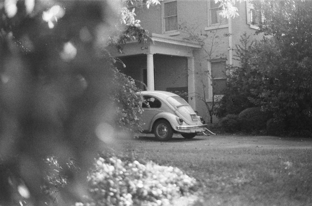 grayscale photo of car near tree