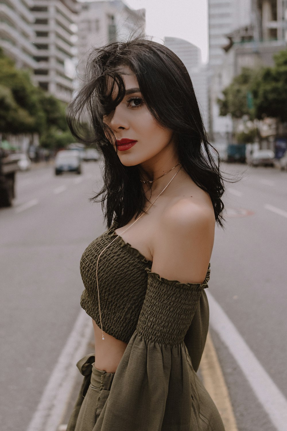 woman in green off shoulder shirt standing on road during daytime