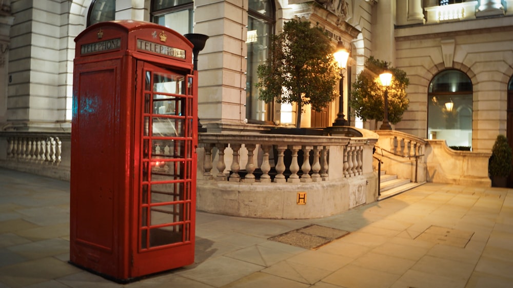 red telephone booth near green trees during daytime