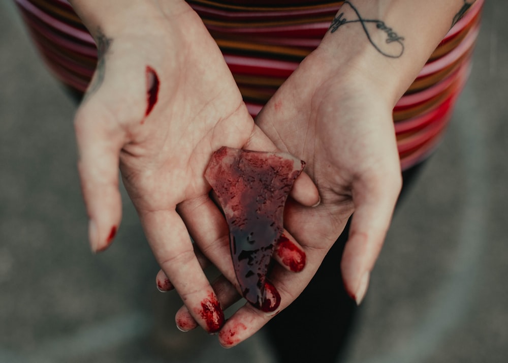 Persona sosteniendo un fragmento de piedra roja y negra
