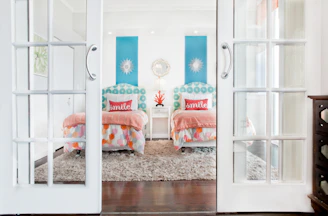 white french doors open to two tropical twin beds in bedroom