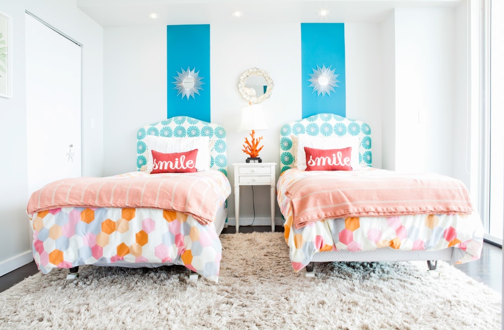 white and red throw pillows on white and blue floral bed