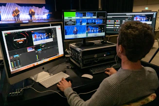 man in gray sweater sitting in front of silver imac